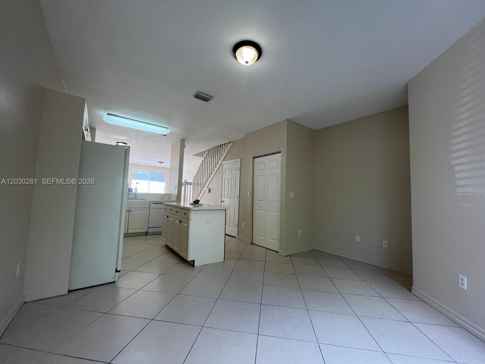 This kitchen and dining area features white cabinets, a central island, and tile flooring — 1932 Alamanda Way # 1932, Riviera Beach FL 33404, RIVIERA BEACH, FL