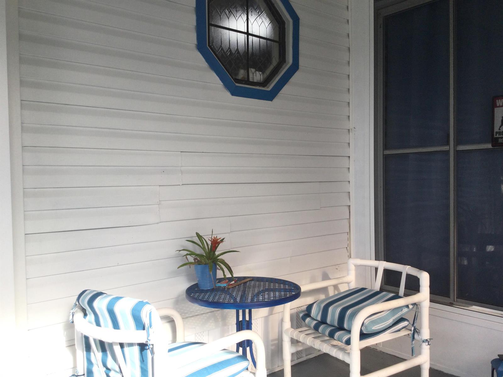 A small blue metal table and two chairs sit on a porch with white siding — 4748 SE Balsawood Terrace, Stuart FL 34997, STUART, FL