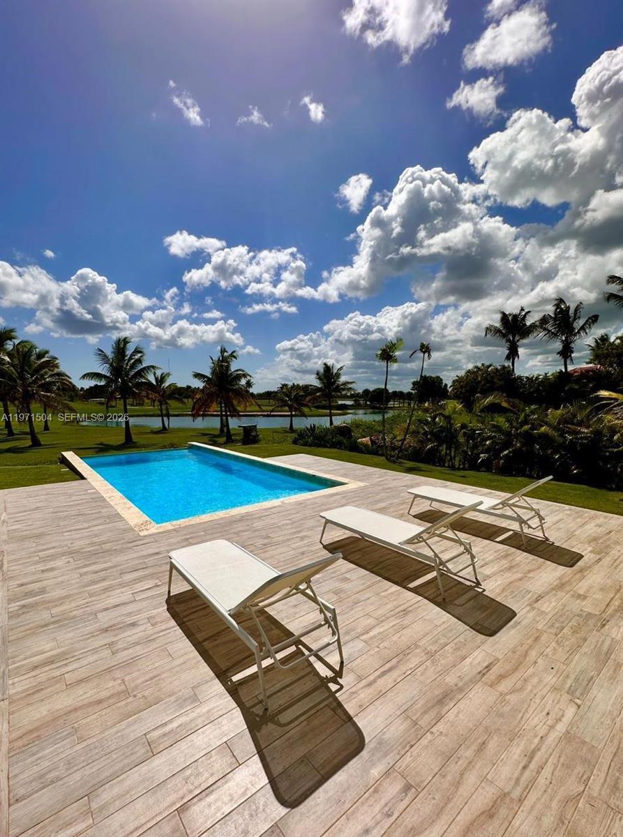 A swimming pool sits on a patio with lounge chairs overlooking a lake and palms — Samanes, La Estancia Golf & Country Club, DR, DR
