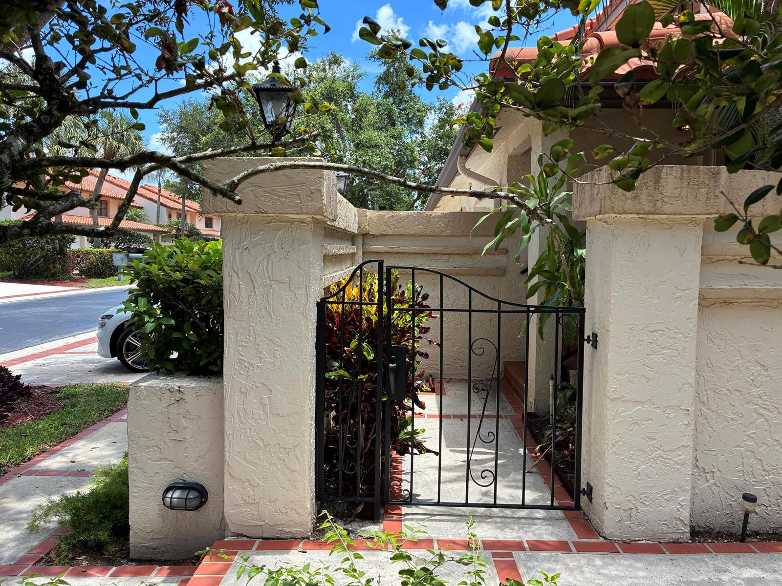 A black metal gate sits between two stucco pillars at the entrance of a home — 7895 La Mirada Drive, Boca Raton FL 33433, BOCA RATON, FL