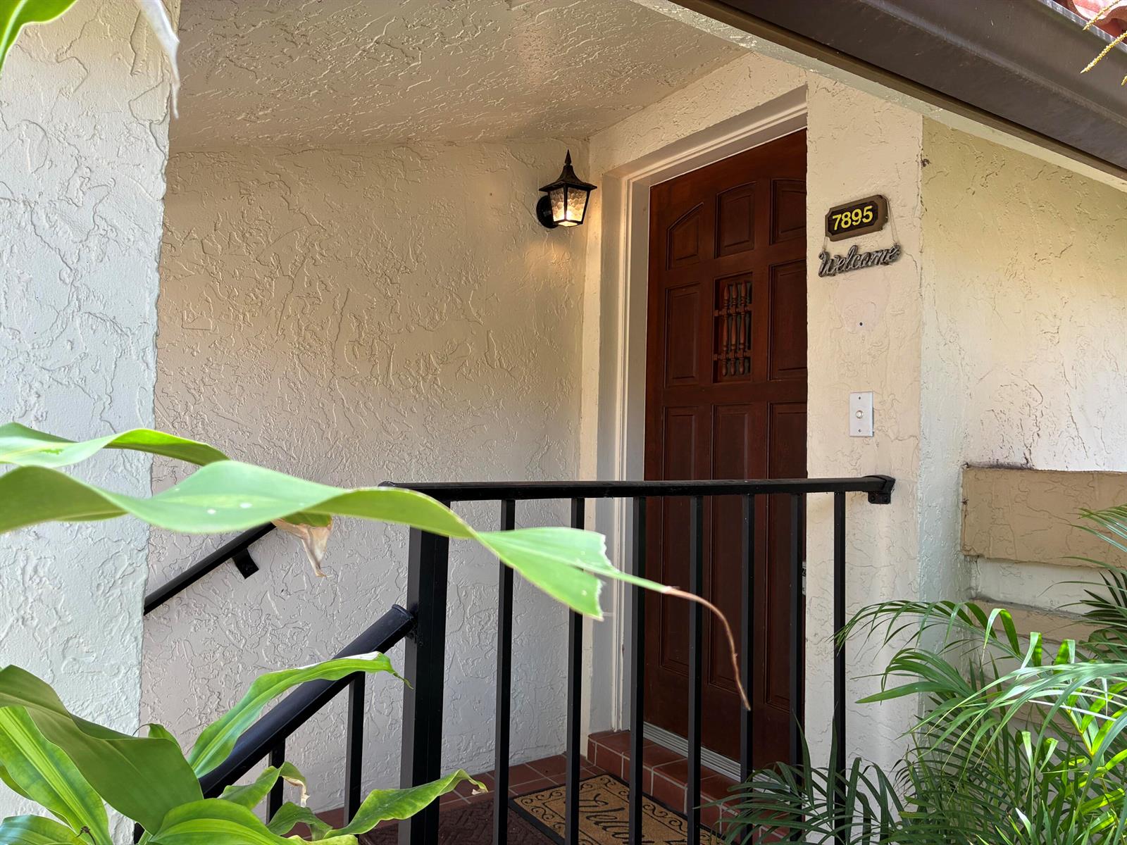 A dark wood front door with a small window is framed by textured stucco walls — 7895 La Mirada Drive, Boca Raton FL 33433, BOCA RATON, FL