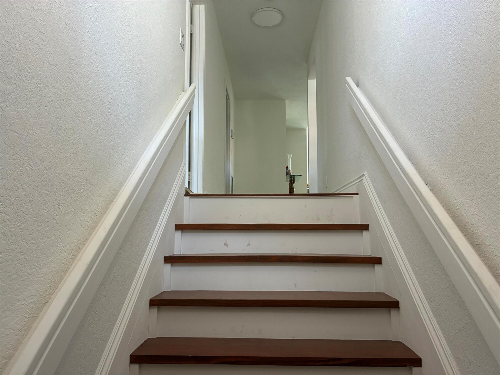 A staircase with wooden treads and white risers leads to a hallway with white walls — 7895 La Mirada Drive, Boca Raton FL 33433, BOCA RATON, FL