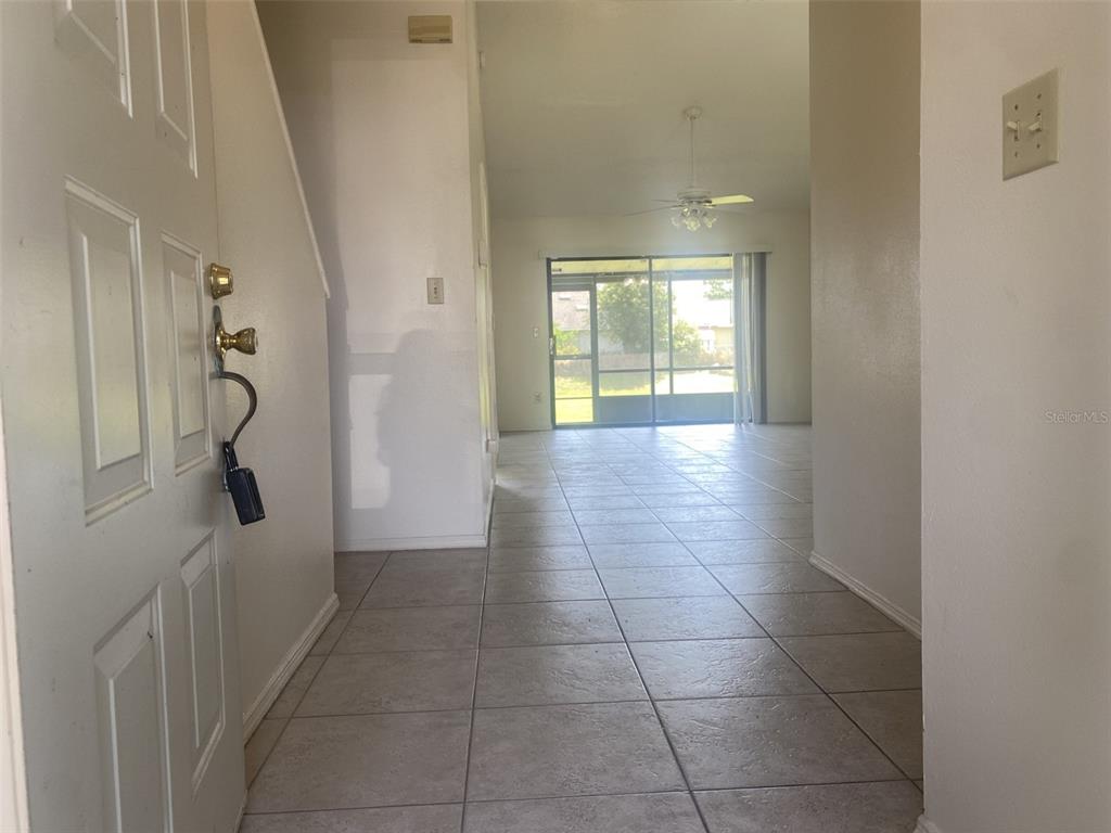 An entryway with tile flooring leads to a living area with a sliding glass door — 42 PINE ISLAND CIRCLE, KISSIMMEE, FL