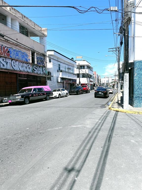 A street view showing a pink and black hearse parked near buildings with graffiti — 2024 LOIZA STREET, SAN JUAN, PR