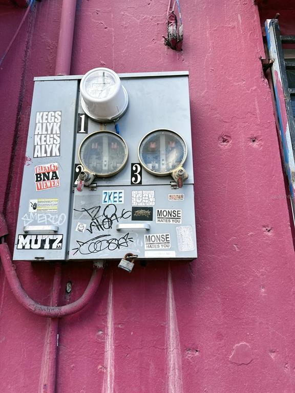 An electrical meter box with graffiti and stickers is mounted on a textured pink wall — 2024 LOIZA STREET, SAN JUAN, PR