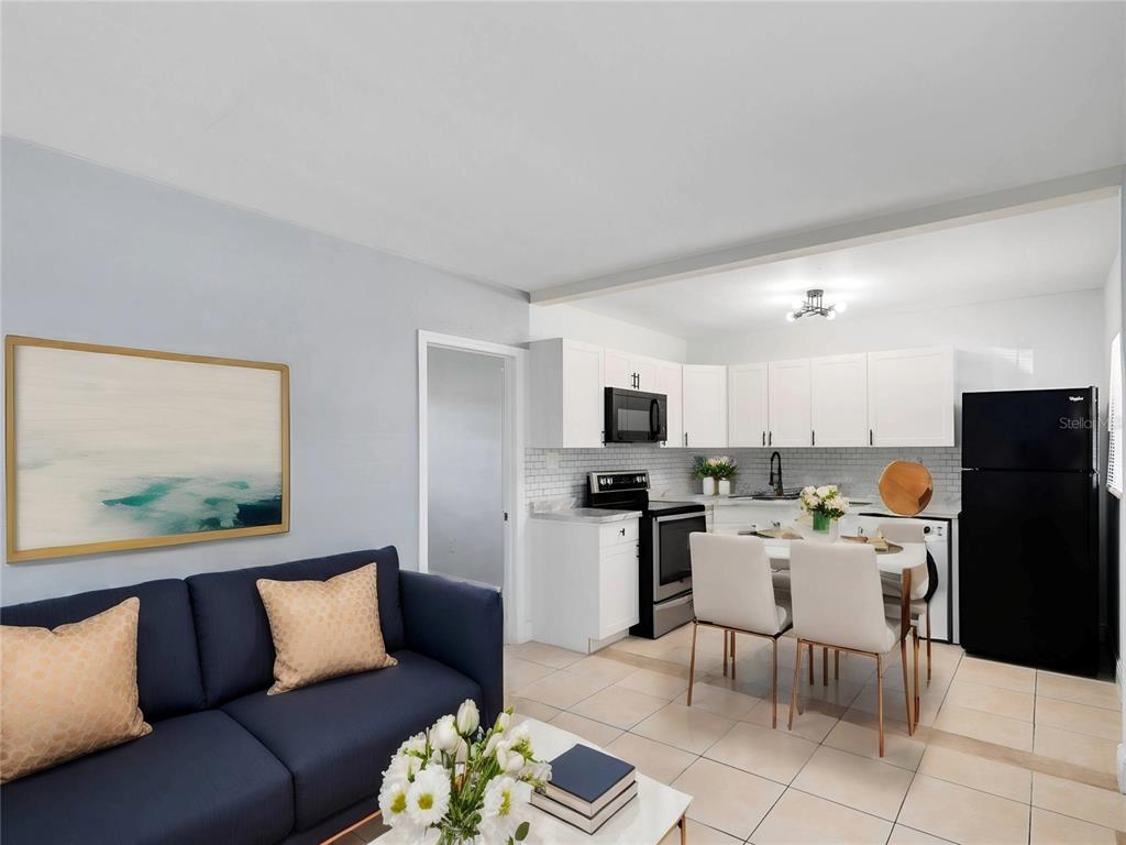 A living room with a blue sofa opens into a kitchen with white cabinets — 955 6TH STREET SE UNIT 5, WINTER HAVEN, FL
