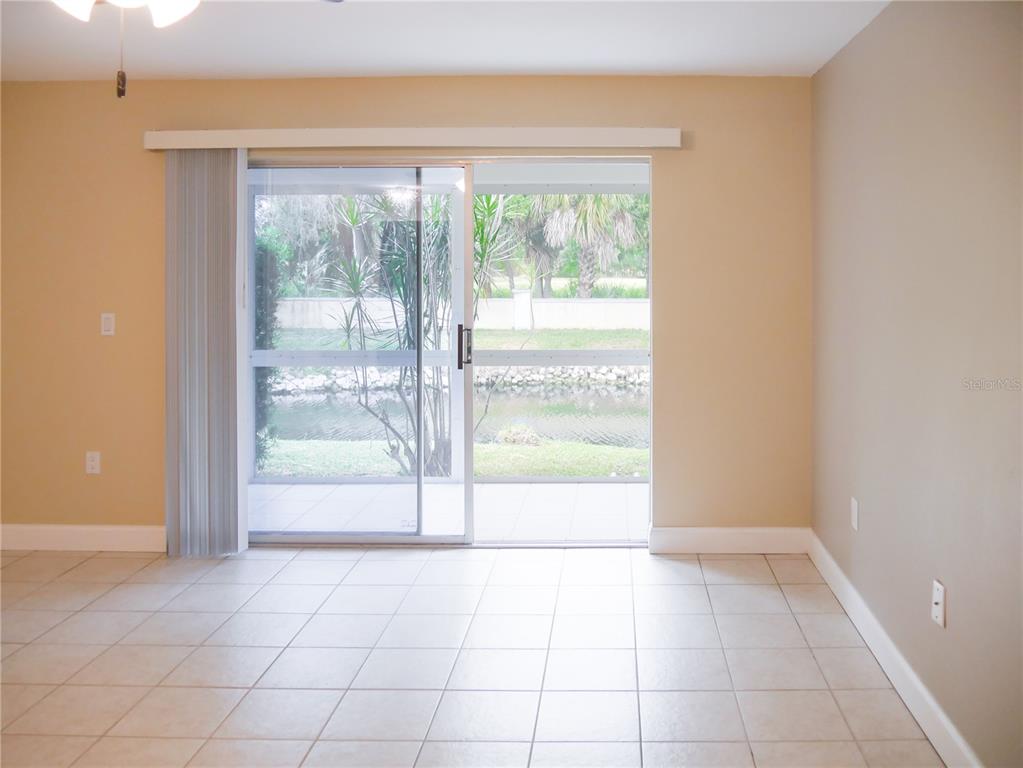 A room with light-colored tile flooring and a sliding glass door overlooking a canal — 2411 ASPINWALL STREET UNIT 2411, SARASOTA, FL