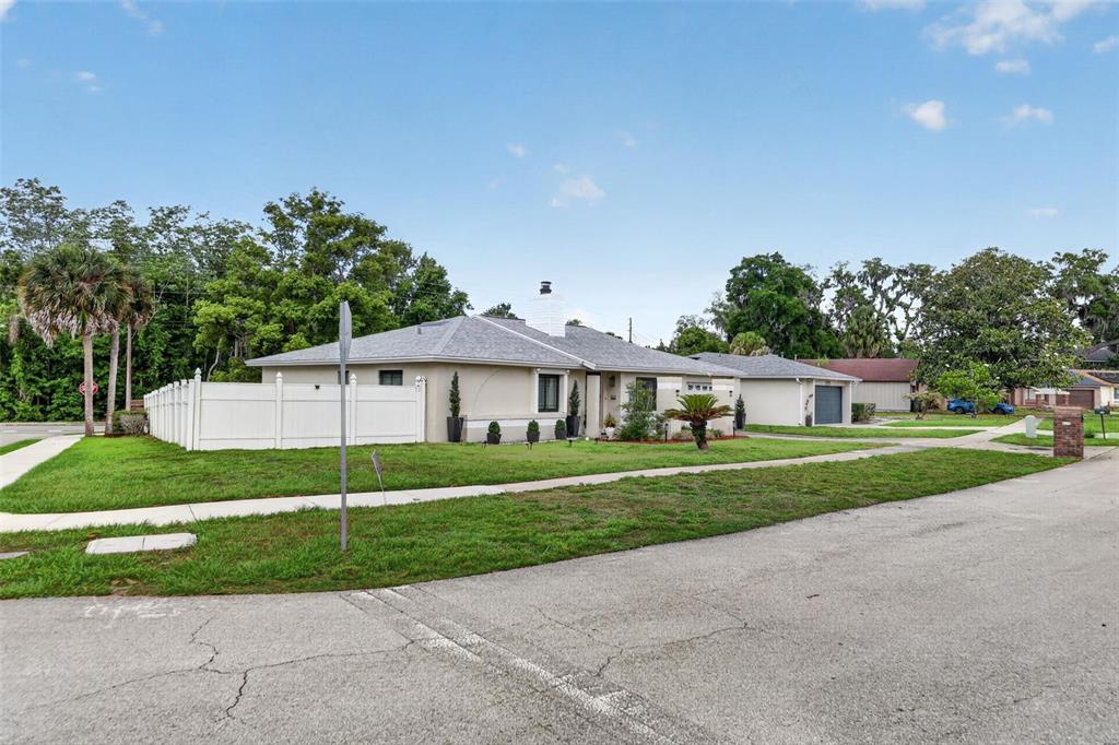 A single-story house with a white fence and a gray roof sits on a corner lot — 575 TIBERON COVE ROAD, LONGWOOD, FL