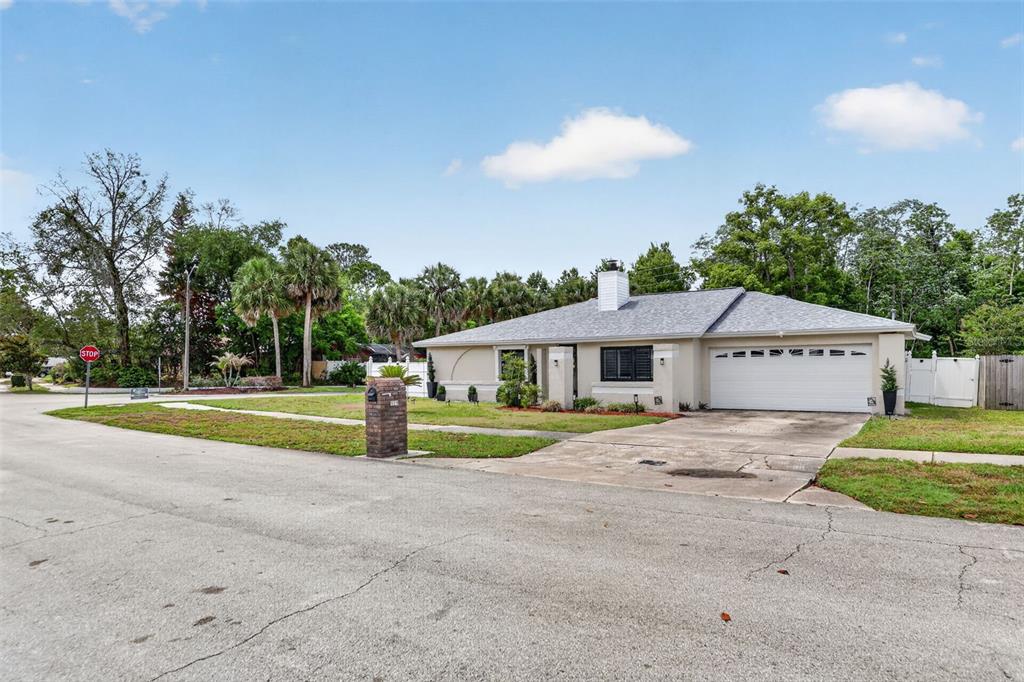 A single-story house with a white garage, brick mailbox, and palm trees on a corner lot — 575 TIBERON COVE ROAD, LONGWOOD, FL