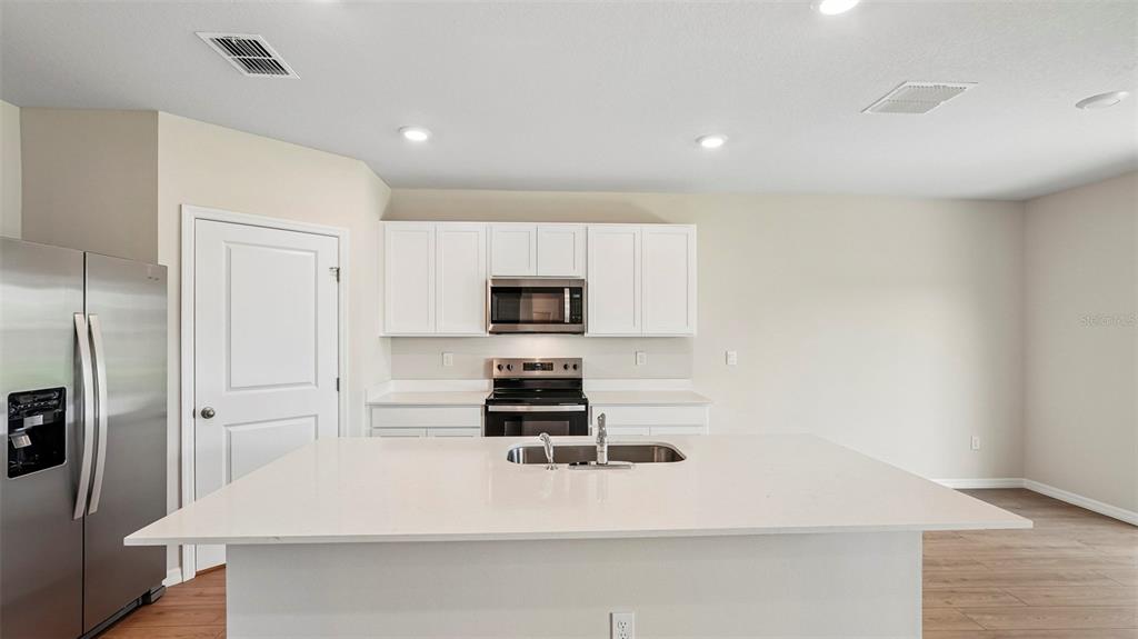A kitchen features white cabinets, stainless steel appliances, a large island, and light-colored countertops — 5423 SILVER MOONLIGHT DRIVE, PALMETTO, FL