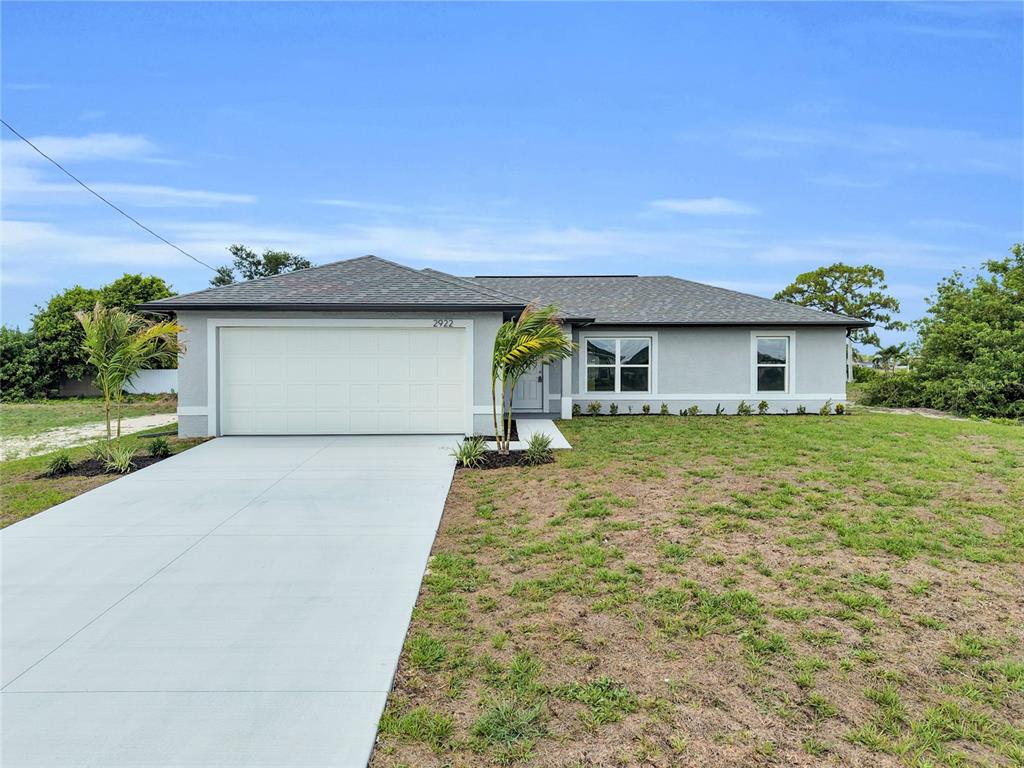A single-story house with a gray exterior, a two-car garage, and a concrete driveway — 310 NE 9TH TERRACE, CAPE CORAL, FL