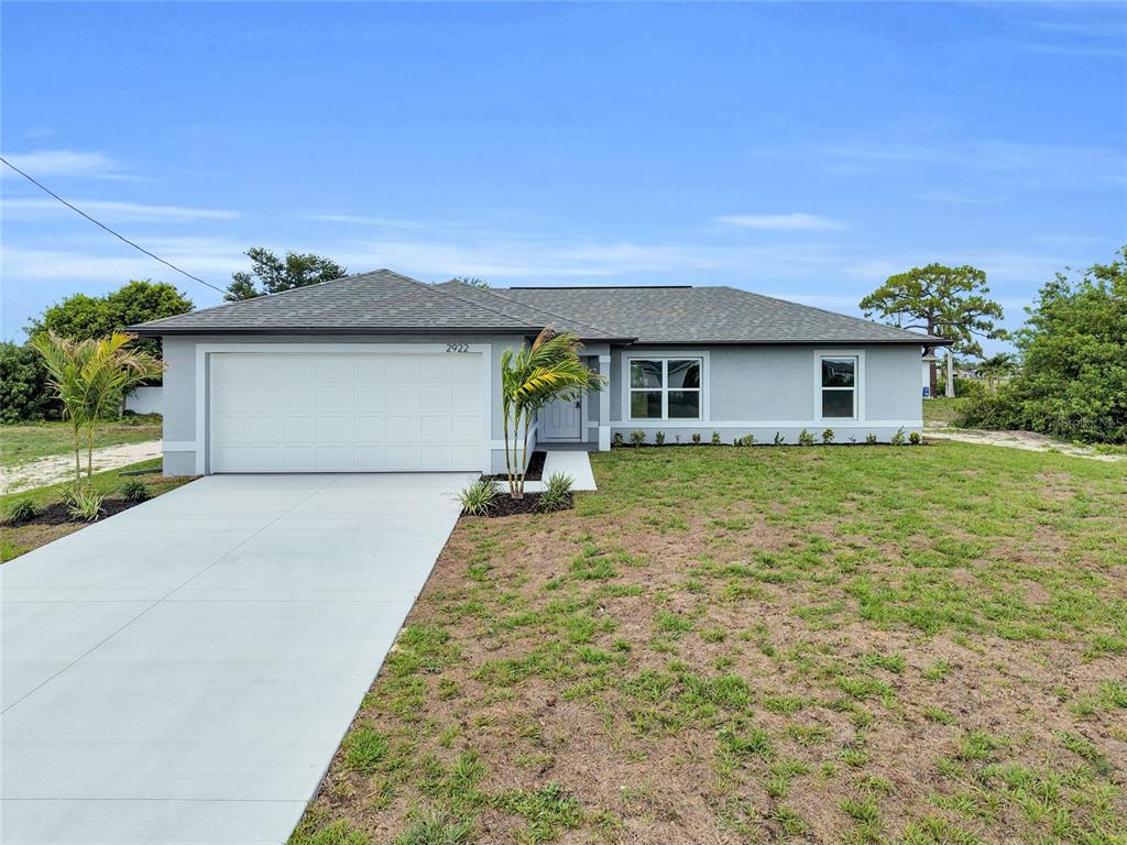 A single-story house with a gray exterior, a two-car garage, and a concrete driveway — 310 NE 9TH TERRACE, CAPE CORAL, FL