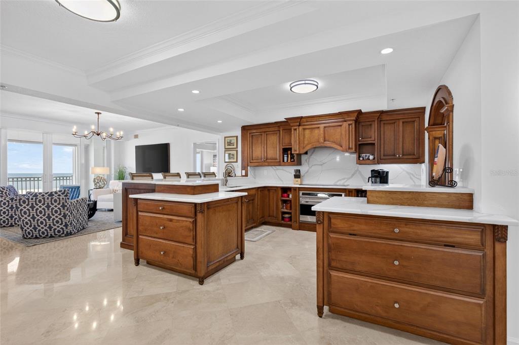 A kitchen with wooden cabinets, white countertops, and a large island overlooks a living area — 200 OCEAN CREST DRIVE UNIT 812, PALM COAST, FL