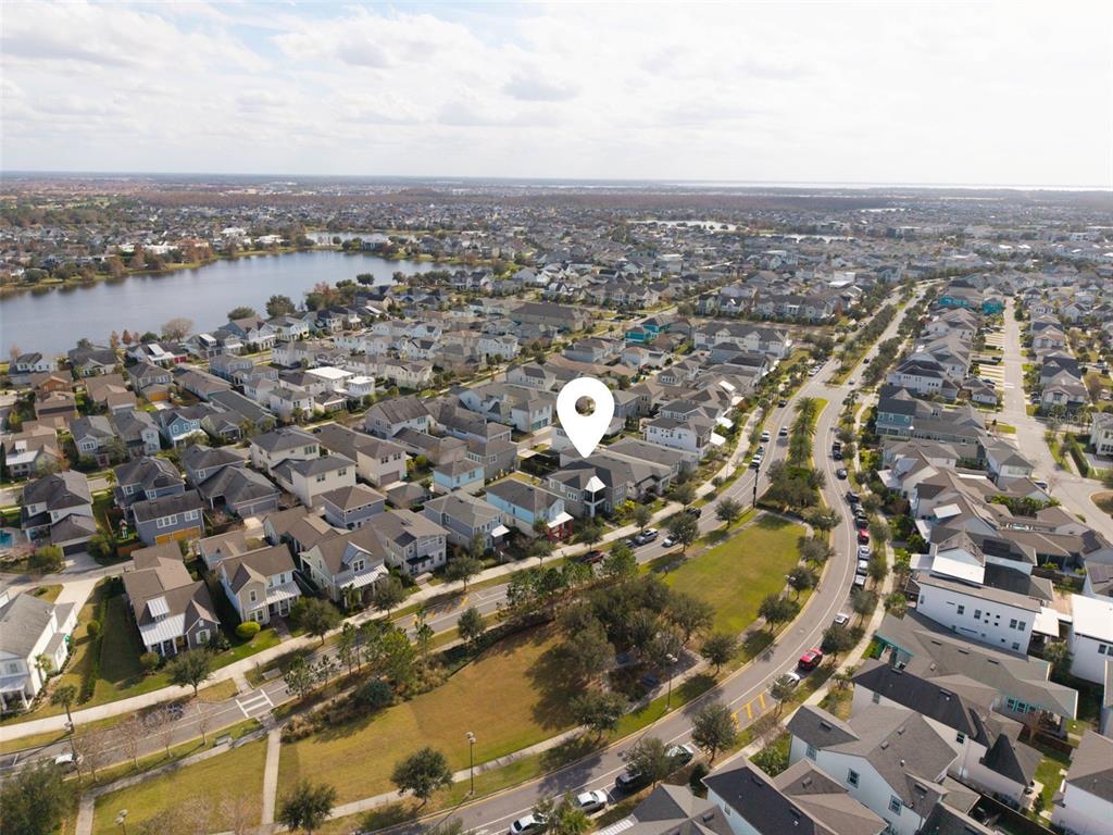 An aerial view shows a suburban neighborhood with houses, a lake, and a park — 8266 NEMOURS PARKWAY, ORLANDO, FL