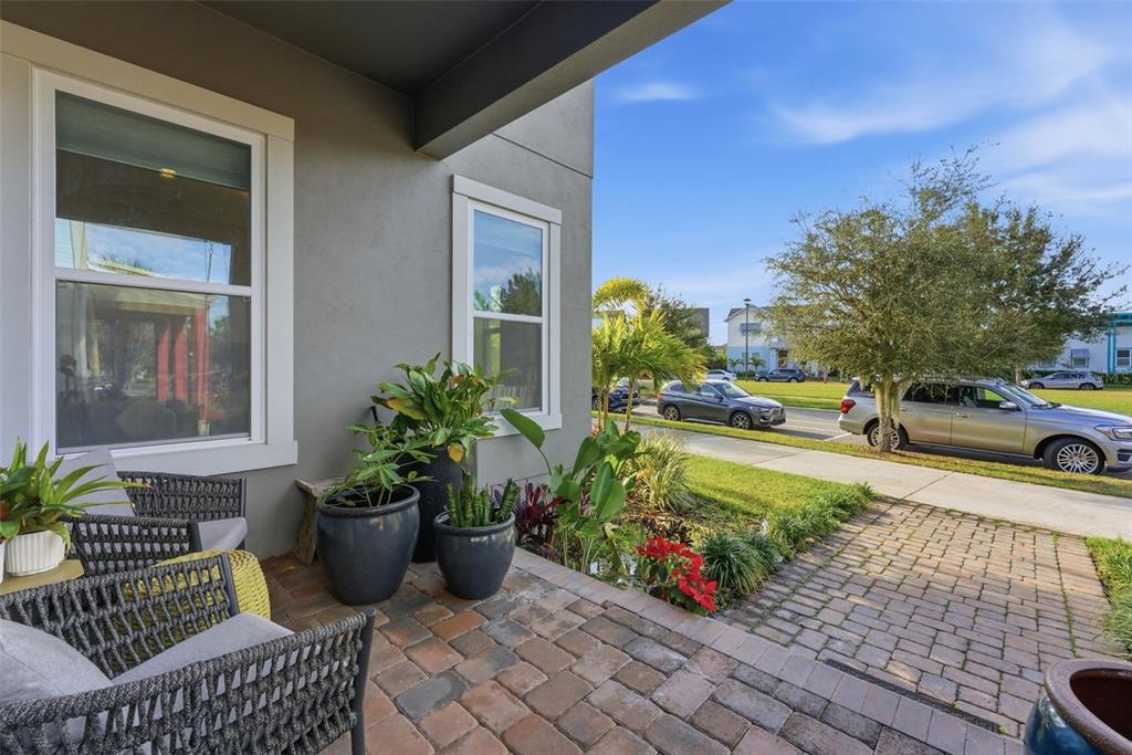 A paved front porch features outdoor seating, potted plants, and a view of the street — 8266 NEMOURS PARKWAY, ORLANDO, FL