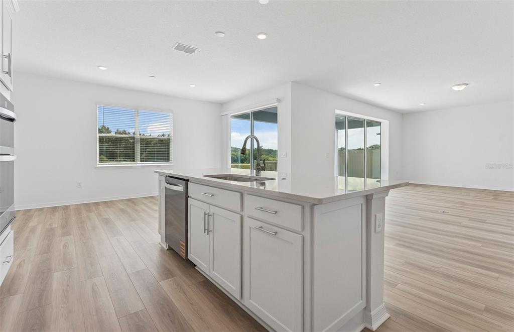 A kitchen island with a stainless steel dishwasher and sink sits in a bright room — 1294 LAKERIDGE WAY, LAKE ALFRED, FL