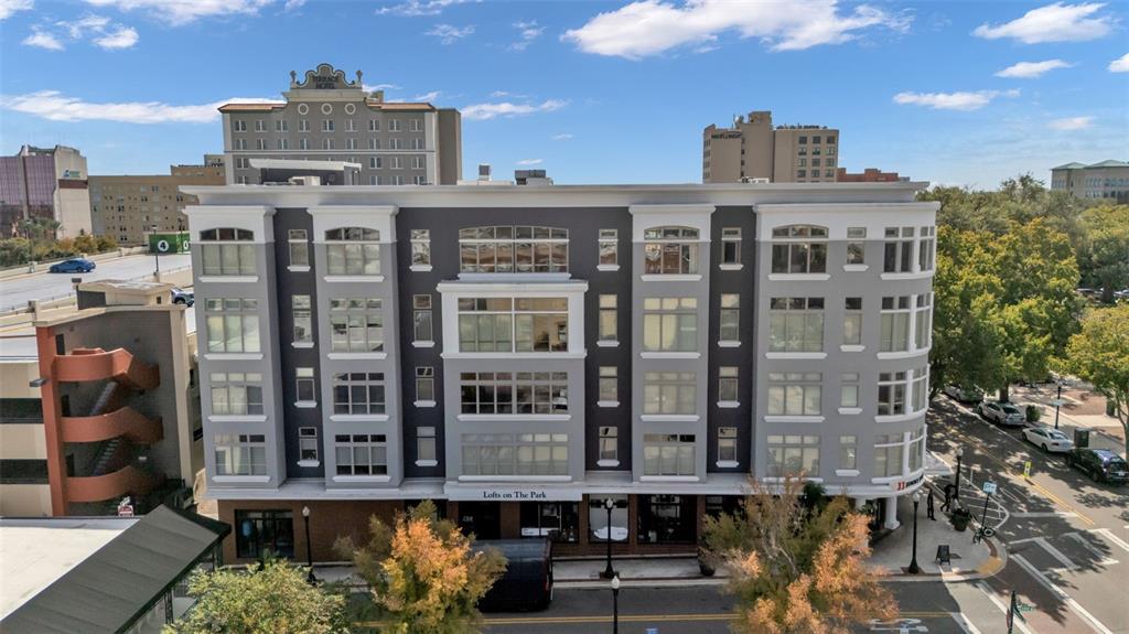 An exterior view of a multi-story gray apartment building with large windows and ground-floor retail — 125 N KENTUCKY AVENUE UNIT 501 & 503, LAKELAND, FL