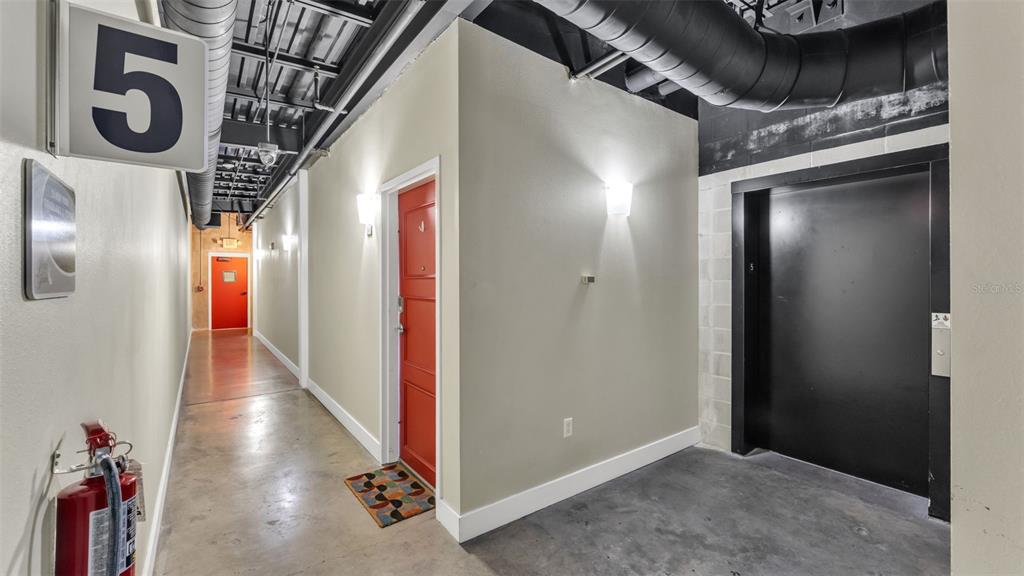 A hallway on the fifth floor features a red door, an elevator, and exposed ductwork — 125 N KENTUCKY AVENUE UNIT 501 & 503, LAKELAND, FL