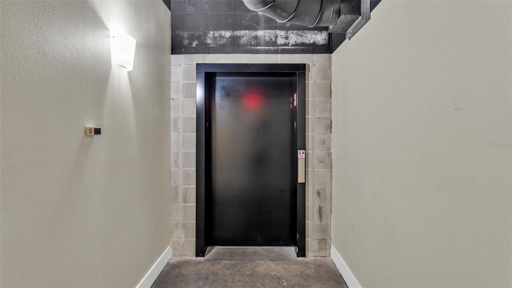 A black elevator door is set within a light-colored concrete block wall in a hallway — 125 N KENTUCKY AVENUE UNIT 501 & 503, LAKELAND, FL