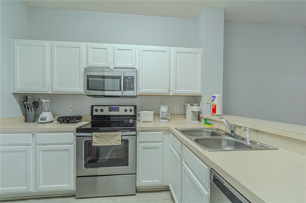 A kitchen features white cabinets, stainless steel appliances, and a double-basin sink on the counter — 8502 CRYSTAL COVE LOOP, KISSIMMEE, FL