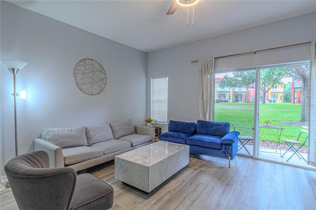 A living room features a gray sofa, a blue loveseat, a marble coffee table, and sliding glass doors — 8502 CRYSTAL COVE LOOP, KISSIMMEE, FL
