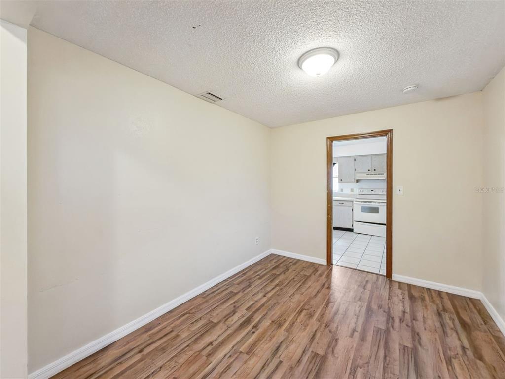 An empty room with wood-look flooring and a doorway leading into a kitchen — 2512 EASTBROOK BOULEVARD, WINTER PARK, FL
