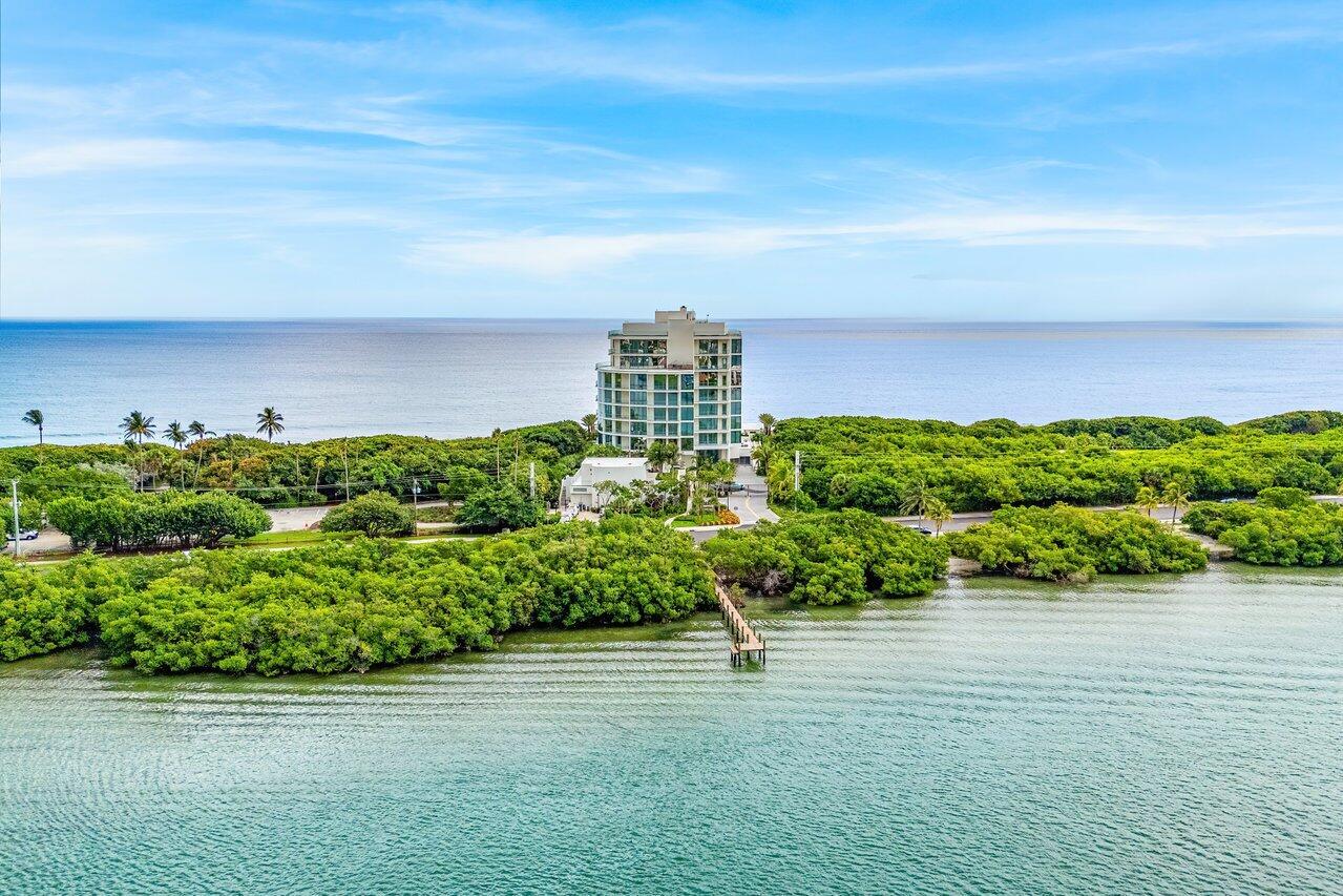 An aerial view shows a tall residential building surrounded by lush trees near the ocean — 1500 S Beach Road # 301, Tequesta FL 33469, TEQUESTA, FL