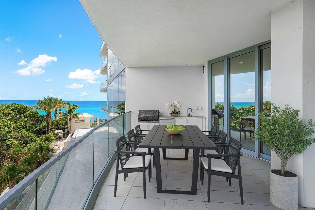 A modern balcony features a dining table, outdoor kitchen, and glass railings overlooking the ocean — 1500 S Beach Road # 301, Tequesta FL 33469, TEQUESTA, FL