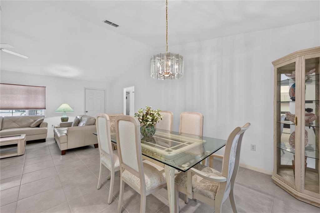 A dining area with a glass-topped table, upholstered chairs, and a crystal chandelier — 15024 SW 112TH CIRCLE, DUNNELLON, FL