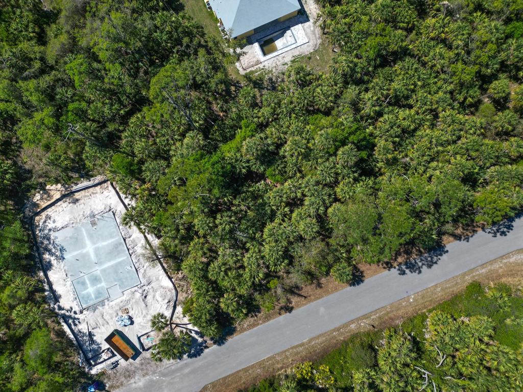 An aerial view shows a concrete foundation under construction next to a paved road — LEESBURG AVENUE, NORTH PORT, FL