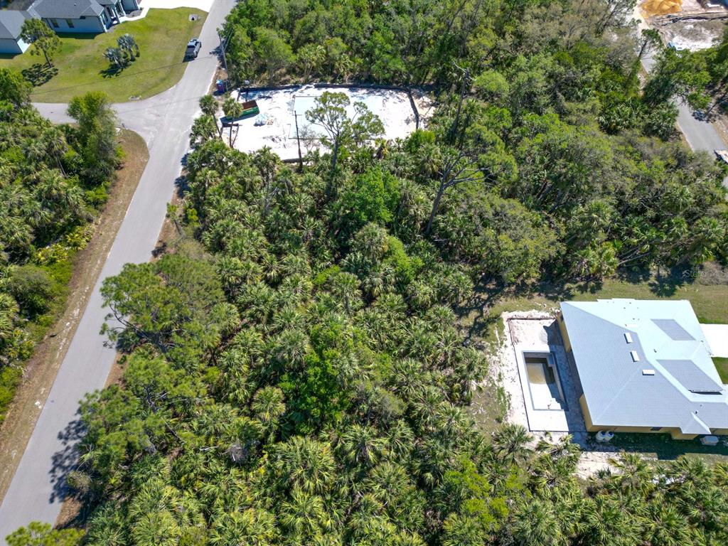 An aerial view shows a wooded lot with a concrete foundation and a nearby house — LEESBURG AVENUE, NORTH PORT, FL