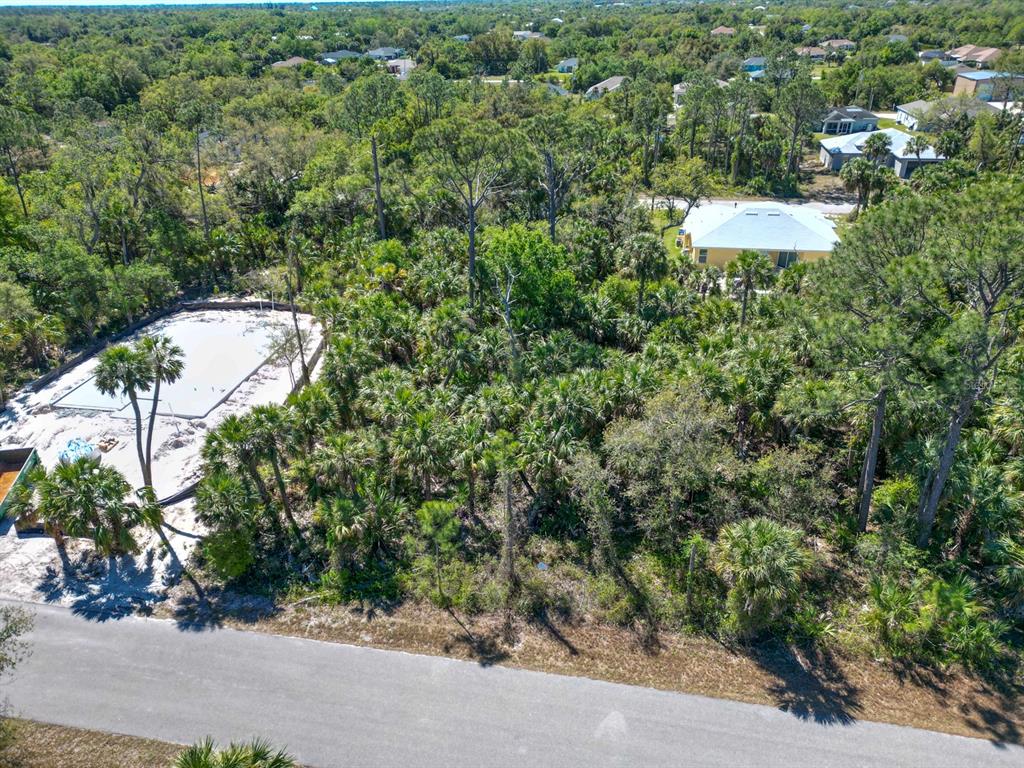 An aerial view shows a concrete foundation under construction next to a wooded residential lot — LEESBURG AVENUE, NORTH PORT, FL