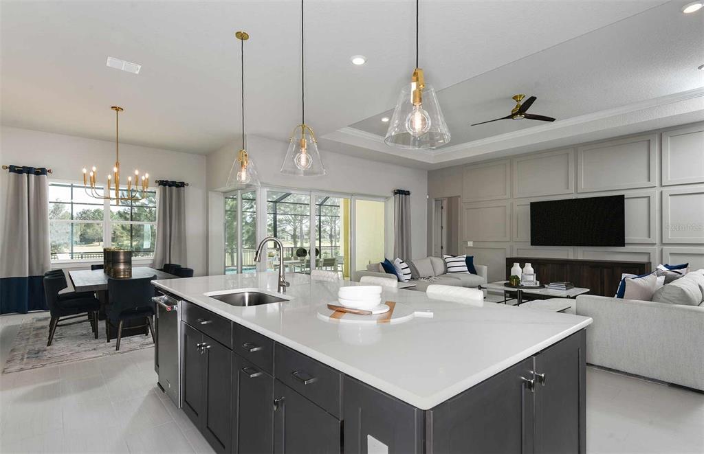 A modern kitchen with a large island overlooks an open-concept living and dining area — 6390 SW 84TH AVENUE, OCALA, FL