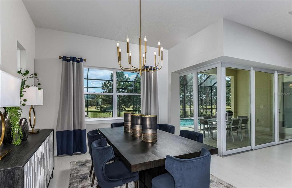 A dining room features a dark wood table, blue chairs, a chandelier, and sliding glass doors — 6390 SW 84TH AVENUE, OCALA, FL