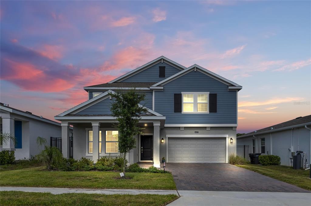 A two-story blue house with a front porch and a two-car garage at sunset — 4519 HILLINGDAM ROAD, DAVENPORT, FL