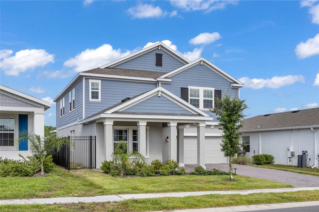 A two-story blue house with a front porch, garage, and a fenced side yard — 4519 HILLINGDAM ROAD, DAVENPORT, FL