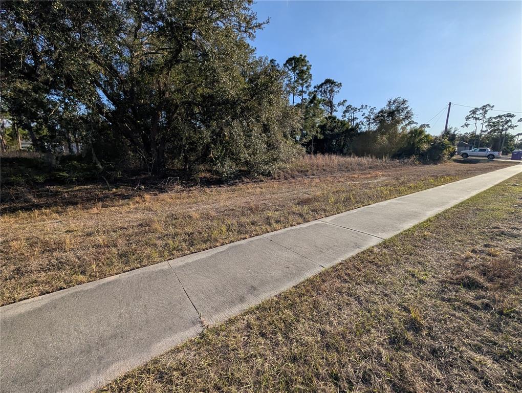 A vacant, grassy lot features a concrete sidewalk and several large trees — Lots 33 & 34 SAN MATEO DRIVE, NORTH PORT, FL