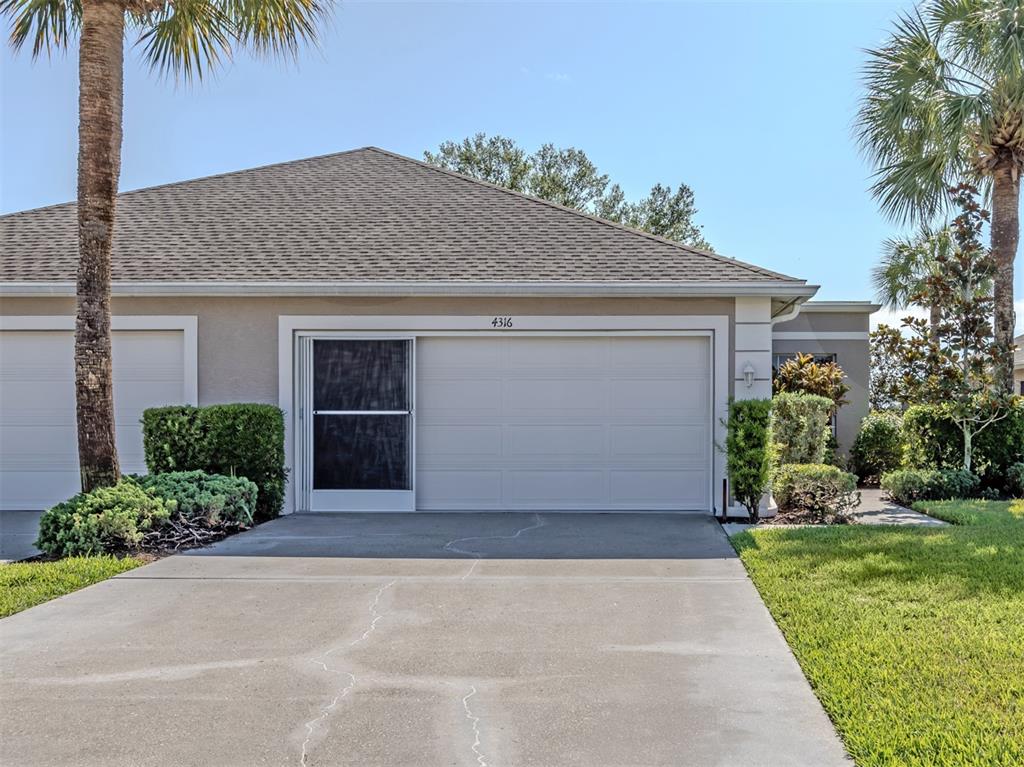 A beige house exterior features a two-car garage with a sliding screen door — 4316 FAIRWAY DRIVE, NORTH PORT, FL