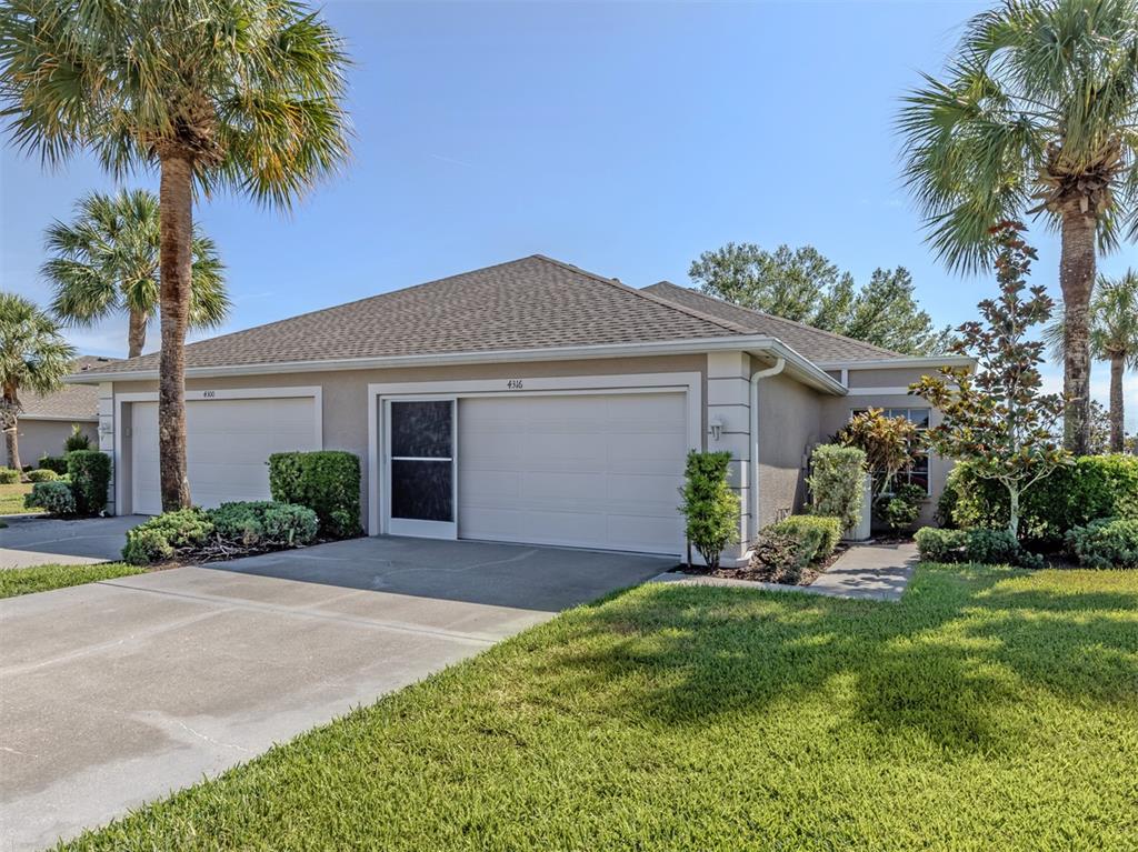 A tan duplex with two garage doors and palm trees under a clear blue sky — 4316 FAIRWAY DRIVE, NORTH PORT, FL