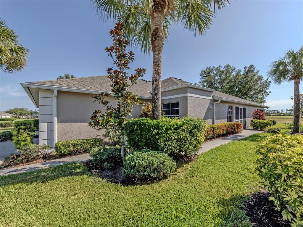 The exterior of a beige house features a palm tree, manicured landscaping, and a concrete walkway — 4316 FAIRWAY DRIVE, NORTH PORT, FL