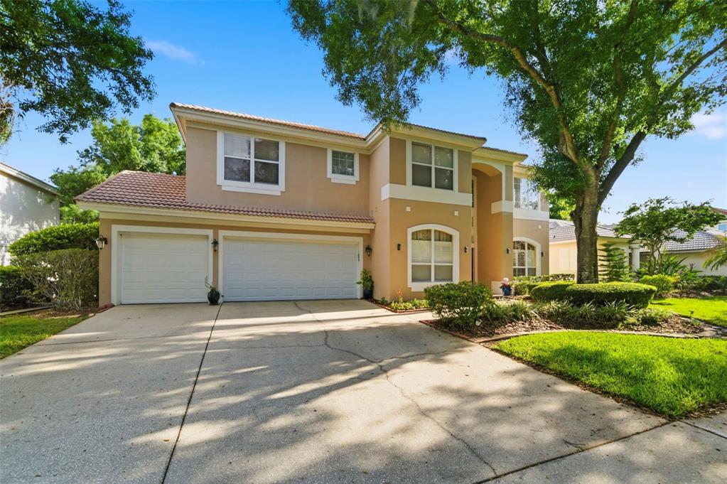 A two-story suburban house with a three-car garage and a concrete driveway — 9207 MEADOW LANE COURT, TAMPA, FL