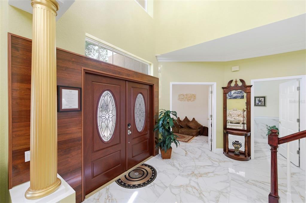 A foyer features a double front door, a gold column, and white marble-look tile flooring — 9207 MEADOW LANE COURT, TAMPA, FL