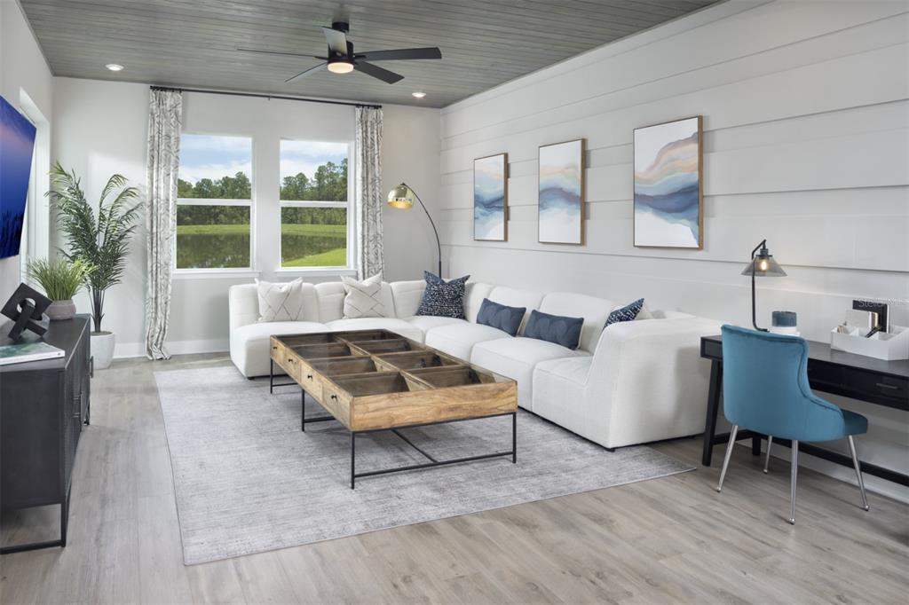 A living room features a white sectional sofa, a wooden coffee table, and a desk area — 17405 MOONFLOWER DRIVE UNIT 102, VENICE, FL