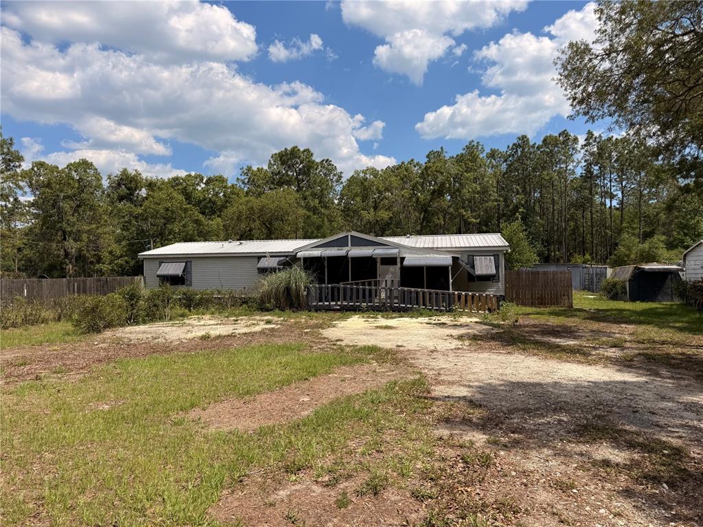 A single-story manufactured home with a front porch and ramp sits on a grassy lot — 7561 SE 120TH COURT, MORRISTON, FL