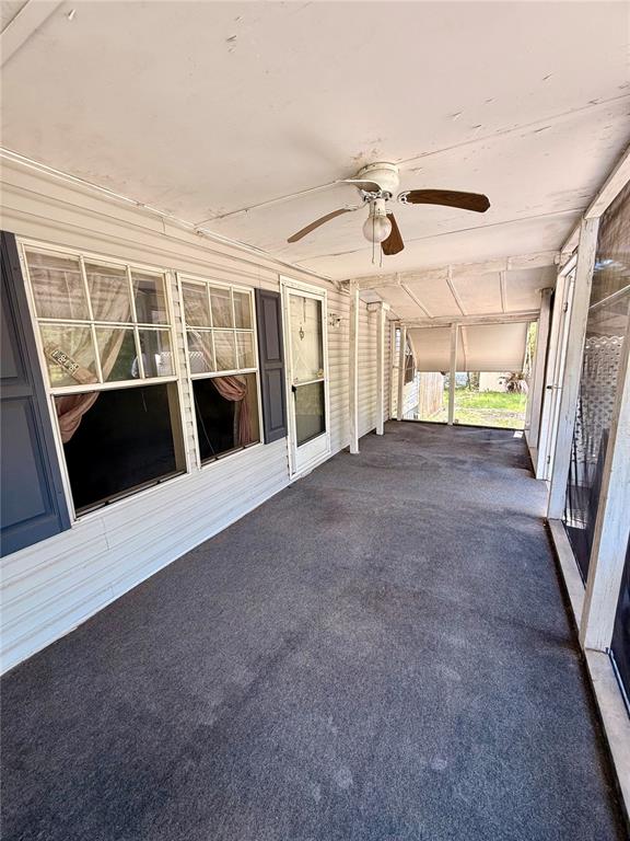 A covered outdoor porch features gray carpeting, a ceiling fan, and white vinyl siding — 7561 SE 120TH COURT, MORRISTON, FL