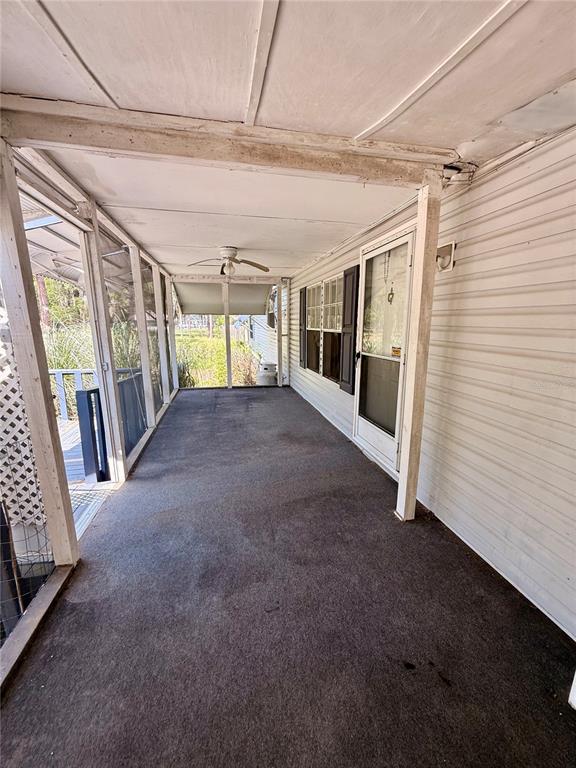 A covered outdoor porch with a ceiling fan, carpeted flooring, and screen walls — 7561 SE 120TH COURT, MORRISTON, FL