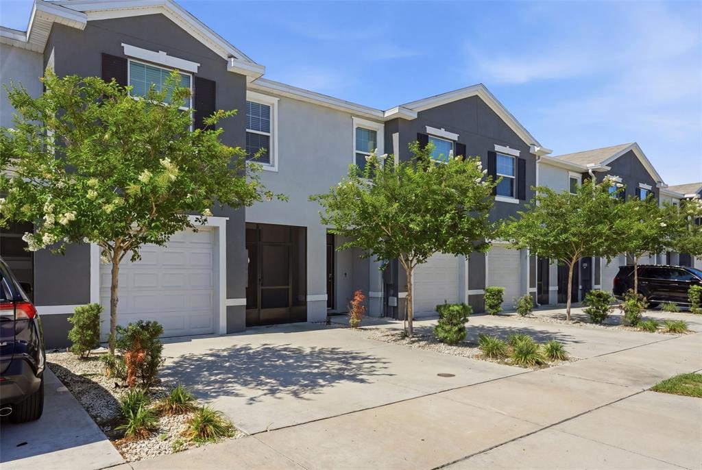 A row of two-story townhomes with gray and white facades, garages, and small front trees — 5267 DRAGONFLY DRIVE, WILDWOOD, FL