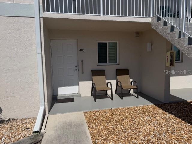 An exterior view of a ground-level apartment entrance with two chairs on a concrete patio — 12538 SW KINGSWAY CIRCLE UNIT 403, LAKE SUZY, FL