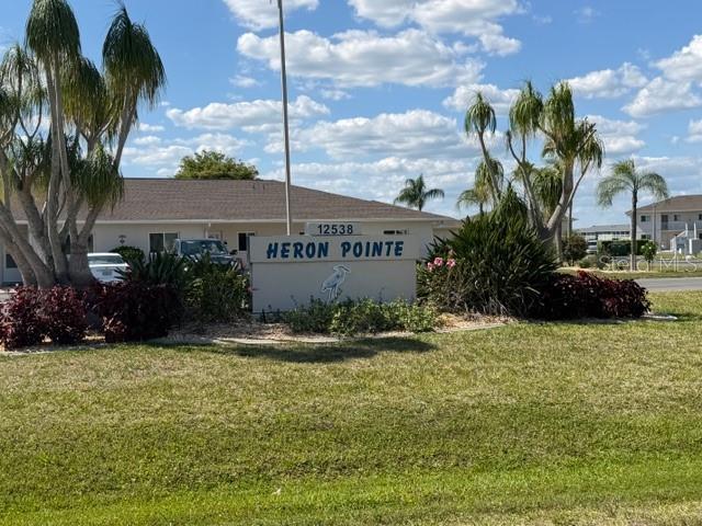 A sign for Heron Pointe stands in front of a residential building with palm trees — 12538 SW KINGSWAY CIRCLE UNIT 403, LAKE SUZY, FL