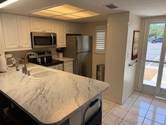 A kitchen features white cabinets, marble-look countertops, stainless steel appliances, and a glass sliding door — 12538 SW KINGSWAY CIRCLE UNIT 403, LAKE SUZY, FL